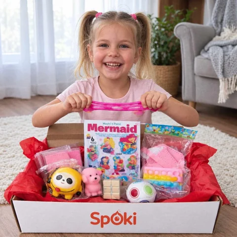 Fată zâmbitoare descoperă o cutie SpOki cu jucării și set creativ