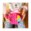 2 genți Pop It unicorn, fetiță ținând în mâini geanta fucsia în formă de cap de unicorn