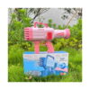 Bazooka pentru baloane de săpun, roz așezată pe cutia produsului, în iarbă.