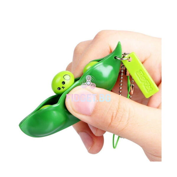 Bob de fasole Fidget, mână care apasă o boabă verde deschis cu chip zâmbitor dintr-o păstaie verde