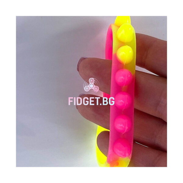 bratari-luminoase-fidget-fucsia-si-portocalii-detaliu-2 Brățări luminoase Fidget, prim-plan cu o brățară roz cu bile galbene, ținută între degete