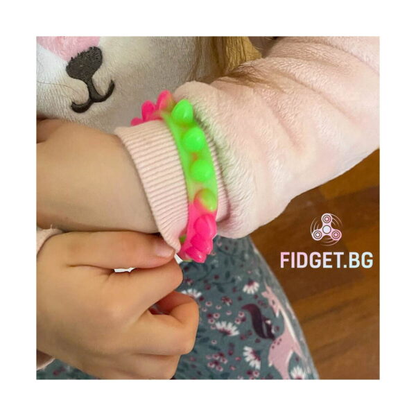 bratari-luminoase-fidget-fucsia-si-portocalii-utilizare-5 Brățări luminoase Fidget, copil cu brățară roz-verde pusă peste mâneca unei bluze roz