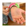 bratari-luminoase-fidget-fucsia-si-portocalii-utilizare-6 Brățări luminoase Fidget, brațul unui copil cu brățara roz-verde peste mânecă, palma deschisă