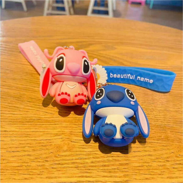 Breloc Lilo & Stitch, brelocurile Stitch roz și albastru pe o masă de lemn, cu curelele imprimate alături