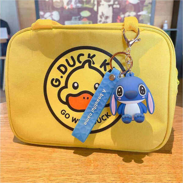 Breloc Lilo & Stitch, Stitch albastru agățat de o geantă galbenă cu imprimeu G.DUCK