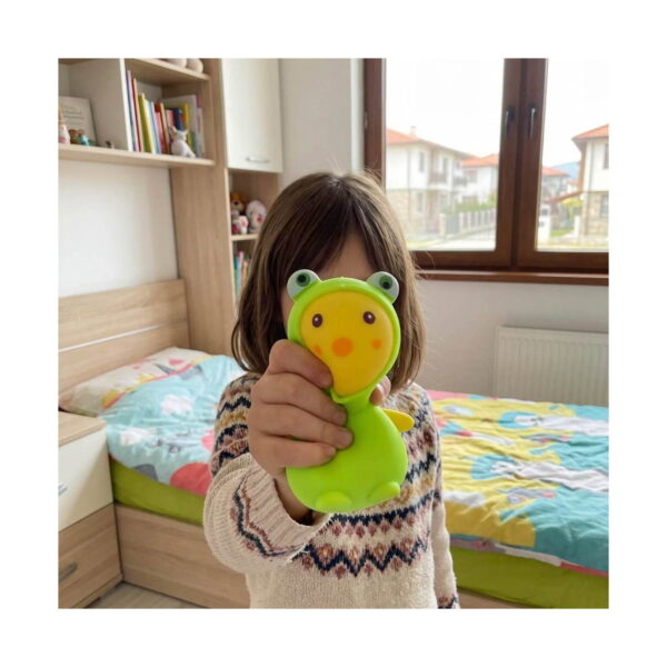 broscuta-bebelus-squishy-utilizare Broscuță bebeluș squishy, fetiță într-o cameră de copii, care ține în mână squishy-ul broscuță