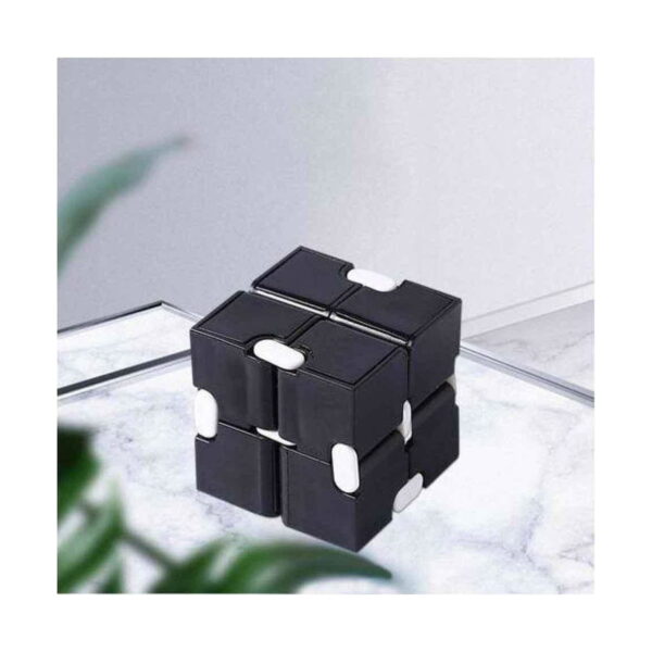 Cub Infinity, negru cu alb așezat pe o suprafață deschisă, lângă o plantă verde