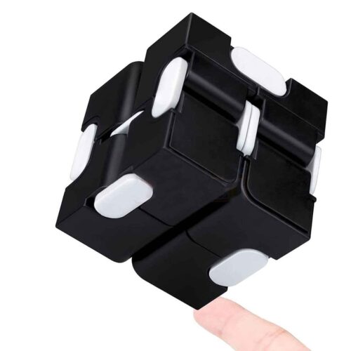 Cub Infinity, negru cu articulații albe, sprijinit pe vârful unui deget, pe fundal alb