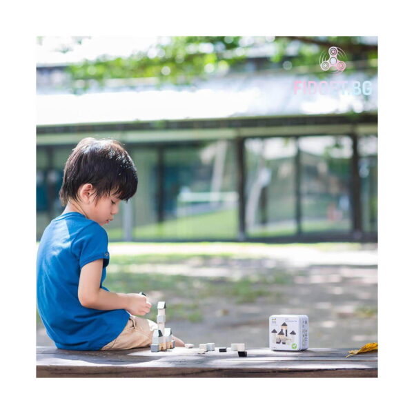 cuburi-constructie-lemn-castel-montessori-utilizare-3 Cuburi construcție, băiat în tricou albastru stă pe jos afară și se joacă cu piese de lemn, lângă cutia setului