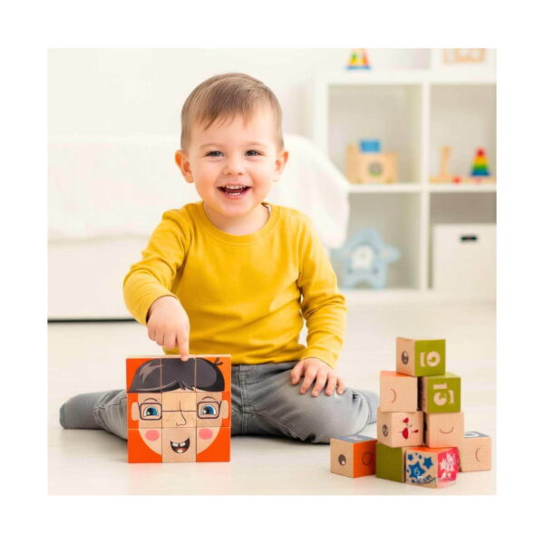 Cuburi Montessori Constructor, băiețel zâmbitor în bluză galbenă, așezat pe podea