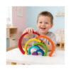 curcubeu-montessori-din-lemn-utilizare Curcubeu Montessori din lemn, băiat zâmbind la o masă albă, ridicând arcada roșie deasupra celorlalte arcade desfăcute