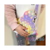 geanta-pop-it-mickey-mouse-15-15-cm-utilizare-2 Geantă Pop It Mickey Mouse, copil în bluză roz ține geanta în fața corpului și apasă bulele