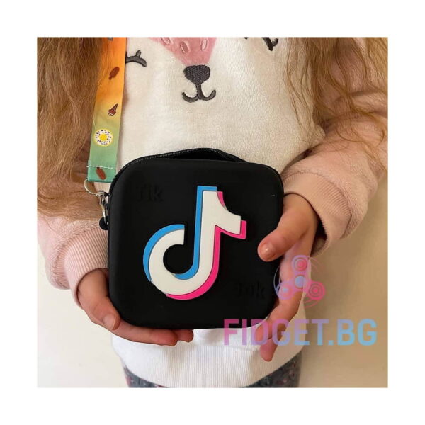 geanta-pop-it-mov-utilizare-2 Geantă TikTok, neagră cu logo, ținută de o fetiță în pulover cu urs, cu bretea colorată