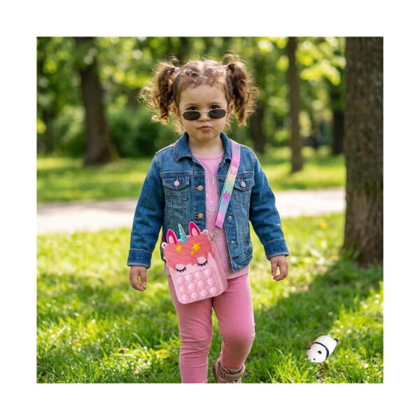 geanta-pop-it-zi-de-nastere-roz-utilizare Geantă Pop It Zi de naștere, fetiță cu ochelari de soare și geacă de blugi, în parc, purtând geanta Pop It unicorn roz