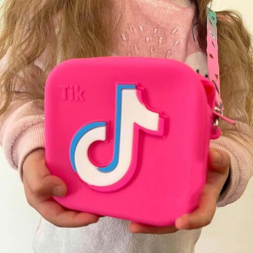 Geantă TikTok, fetiță care ține în mâini o geantă TikTok fucsia din silicon, cu logo TikTok în relief și bretea roz-mentă