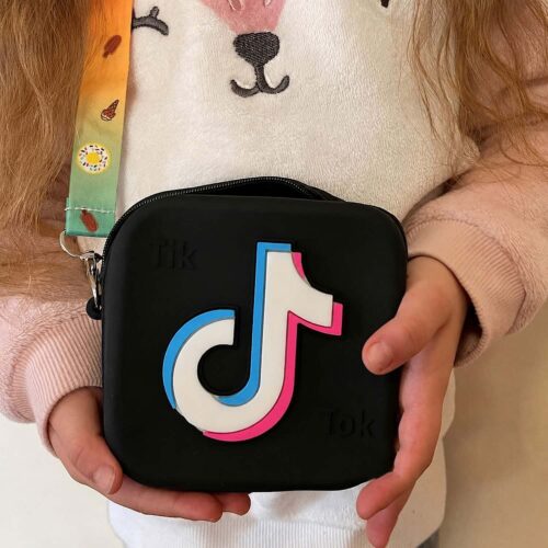Geantă TikTok, fetiță care ține în mâini o geantă TikTok neagră din silicon, cu logo TikTok în relief și bretea colorată
