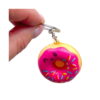 gogoasa-squishy-draguta-cu-capsuna-detaliu Gogoașă squishy drăguță cu căpșună, două degete țin inelul brelocului, iar gogoașa squishy roz atârnă dedesubt