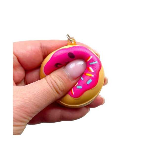 gogoasa-squishy-draguta-cu-capsuna-utilizare-2 Gogoașă squishy drăguță cu căpșună, o mână strânge gogoașa squishy, degetul mare înfundă glazura roz