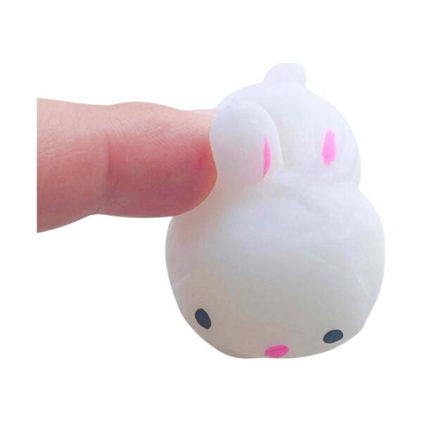 Iepuraș drăgălaș squishy, un deget apasă spatele iepurașului squishy alb și îl deformează