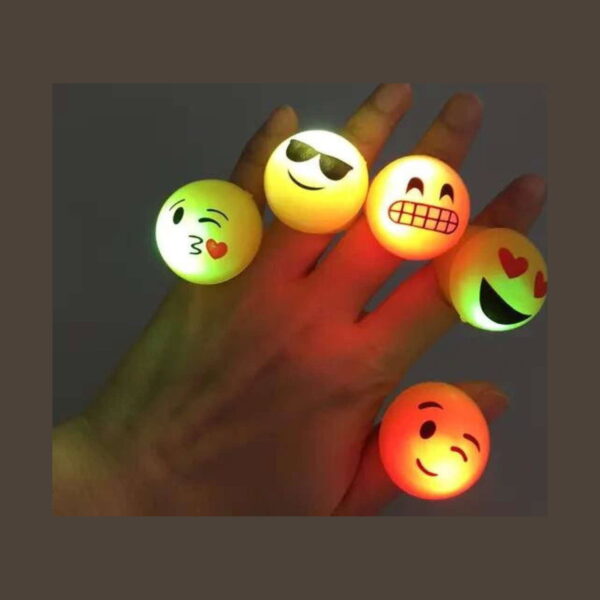 inel-squishy-emoji-utilizare Inel squishy Emoji, cinci inele emoji aprinse, purtate pe degetele unei mâini, în lumină slabă