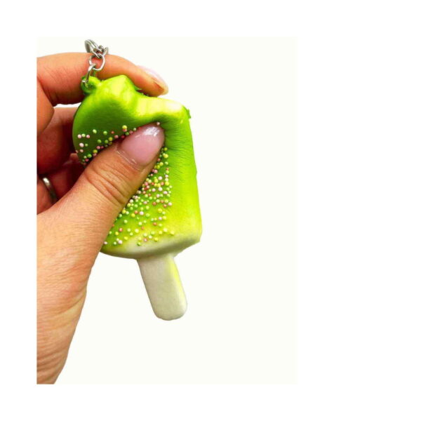 inghetata-squishy-cu-parfum-delicat-utilizare-3 Înghețată squishy cu parfum delicat, o mână strânge înghețata verde, materialul turtindu-se sub degete