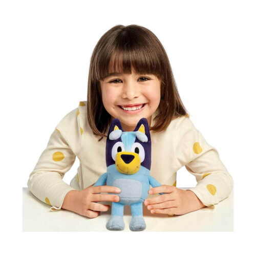 Jucărie de pluș Bluey, fetiță brunetă cu bluză crem cu buline galbene, așezată la masă