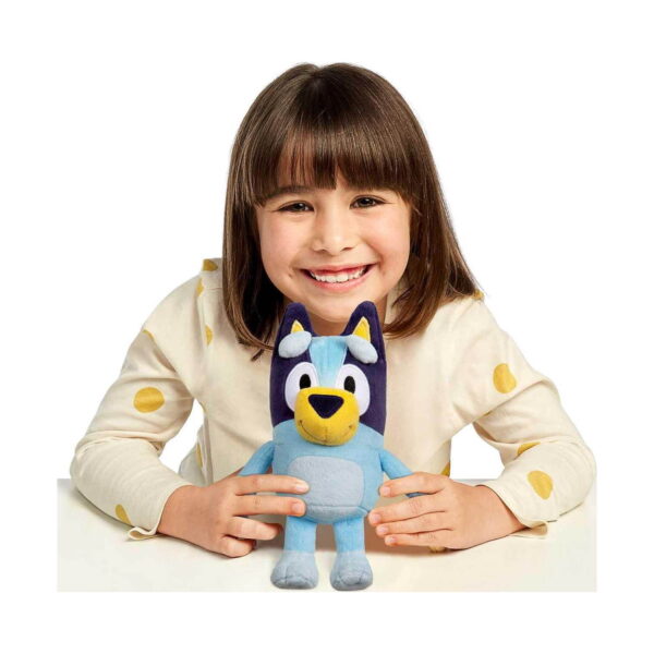 jucarie-de-plus-bluey-albastra-utilizare Jucărie de pluș Bluey, fetiță brunetă cu bluză crem cu buline galbene, așezată la masă