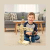 kit-stem-macara-din-lemn-utilizare Kit STEM Macara din lemn, un băiat stă pe covor în sufragerie, ține telecomanda și privește macaraua din lemn asamblată