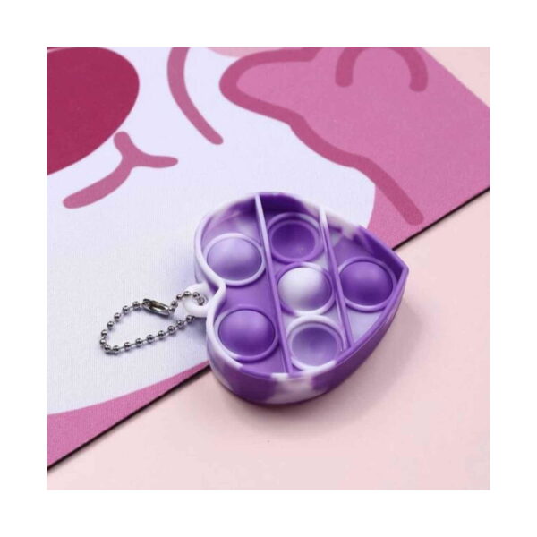 mini-pop-it-inimioara-detaliu Mini Pop It inimioară, prim-plan cu mini Pop It inimă mov, cu bulele apăsate, pe fundal roz