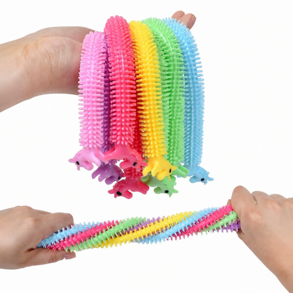Monkey Noodles unicorn, sus: o mână peste care atârnă mai multe jucării unicorn colorate; jos: două mâini întind un mănunchi