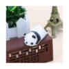 Panda squishy moale, stă pe o piesă decorativă din lemn închis, lângă o plantă verde