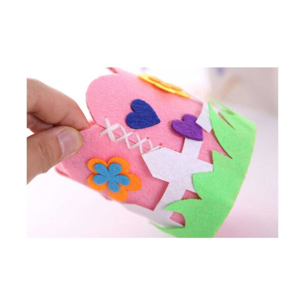 penar-diy-pentru-copii-fericire-roz-detaliu Penar DIY pentru copii Fericire roz, o mână ține marginea suportului; se văd cusătura albă și aplicațiile cu inimi mov