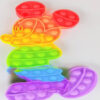 Pop It colorat Mickey Mouse 30x20, din silicon în formă de Mickey Mouse, în culorile curcubeului, pe fundal gri deschis