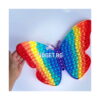 Pop It Fluture Maxi, o mână ține fluturele Pop It curcubeu pe un fundal alb-albăstrui