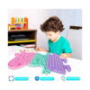 Pop It Peppa Pig, băiat în tricou verde la o masă apasă bulele jucăriei, cu trei etichete în partea de jos