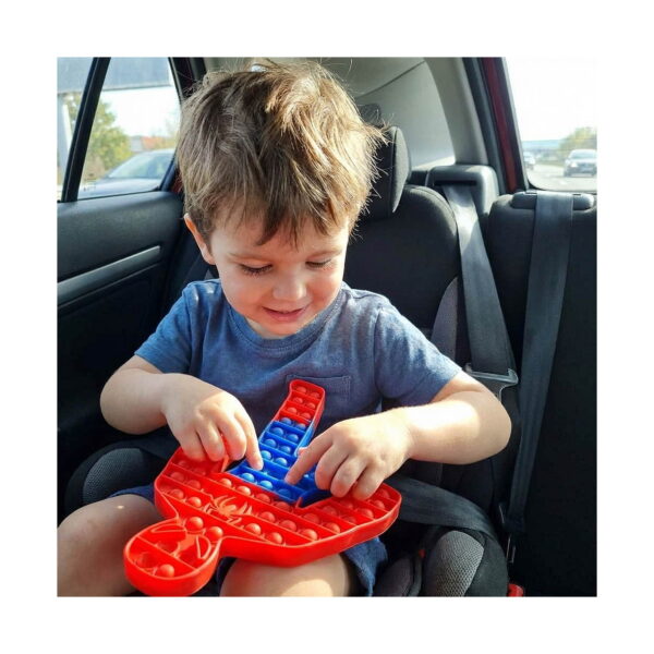 Pop It Spider-Man, un băiețel în scaunul auto apasă bulele Pop It-ului Spider-Man, roșu cu tors albastru, ținut în poală