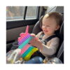 Pop It unicorn, copil mic în scaun auto ține unicornul Pop It în poală