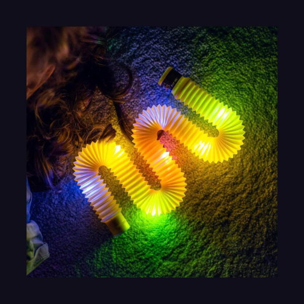 pop-tube-rosu-lifestyle-3 Tub Fidget Pop luminos XL, tuburi luminoase galbene și albe, aranjate pe covor în întuneric