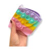 portofel-pentru-copii-fluture-curcubeu-dimensiuni-2 Portofel pentru copii Fluture, o mână ține portofelul pastel pliat, cu aripile Pop It în față