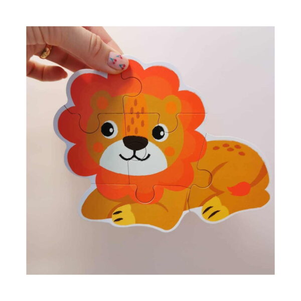 Puzzle animale, o mână așază ultima piesă a puzzle-ului cu leu, în portocaliu și galben, pe fundal deschis