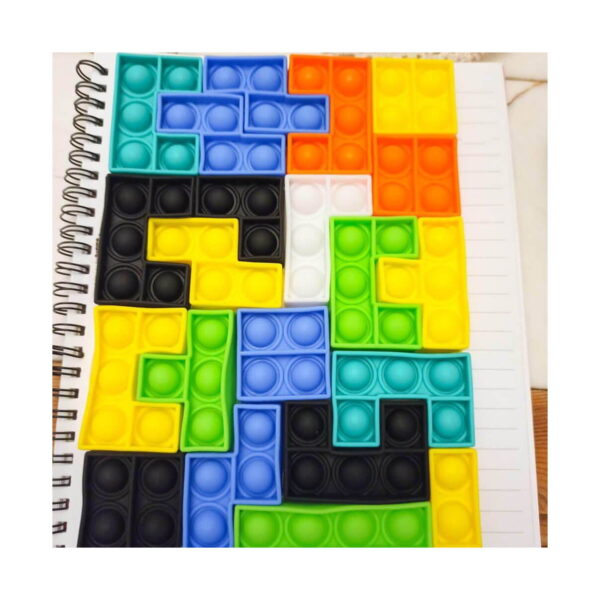 puzzle-distractiv-zi-de-nastere-utilizare Puzzle distractiv Zi de naștere, pop It tetris asamblat complet, așezat pe un caiet cu spirală, pe o masă de lemn