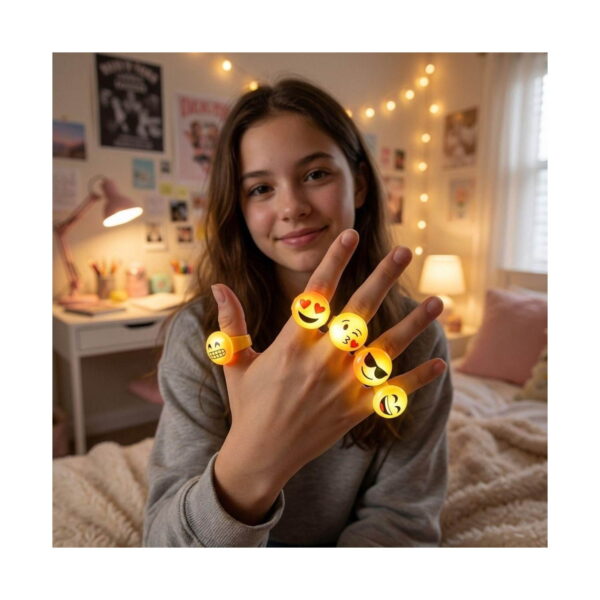 set-3-inele-emoji-luminoase-utilizare Set 3 inele Emoji luminoase, o adolescentă într-o cameră cu ghirlande luminoase arată spre cameră mâna cu patru inele emoji