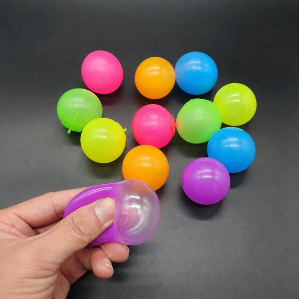 set-4-bile-sticky-balls Set 4 bile Sticky Balls, mai multe bile lucioase în culori diferite (roz, portocaliu, albastru, verde) pe o suprafață gri