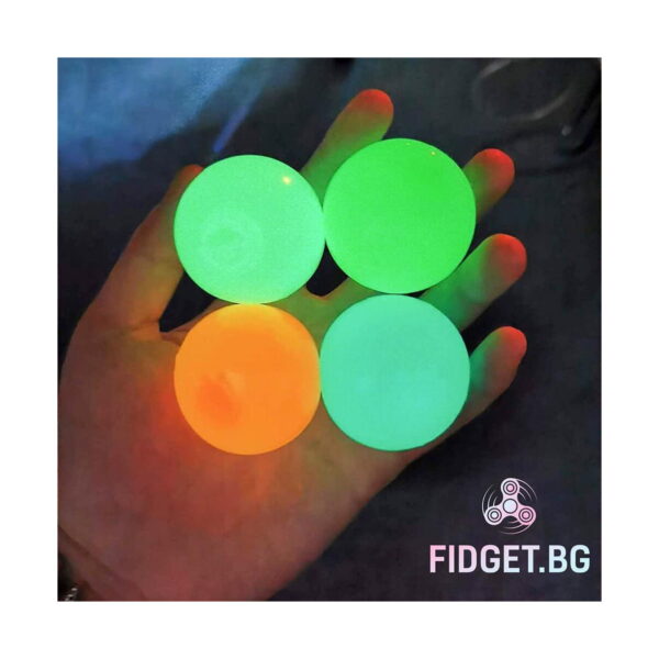 set-4-bile-sticky-balls-iluminat-2 Set 4 bile Sticky Balls, patru bile fosforescente (una portocalie, trei verzi) în palma unei mâini, în întuneric