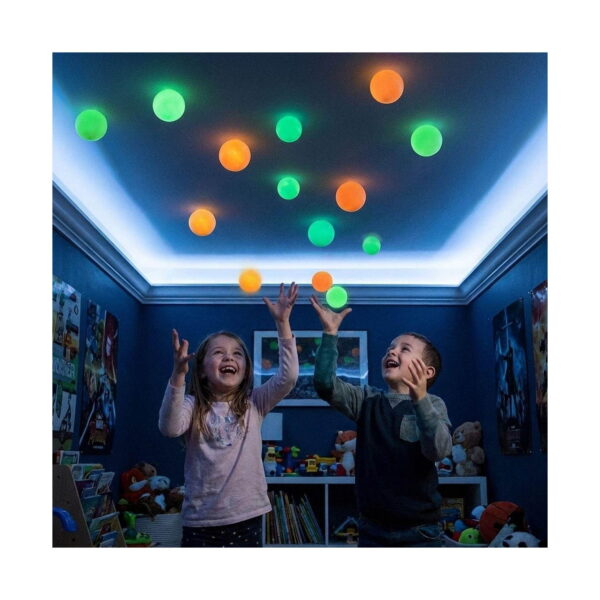 set-4-bile-sticky-balls-utilizare Set 4 bile Sticky Balls, doi copii într-o cameră albastră ridică mâinile spre tavanul pe care sunt lipite multe bile verzi