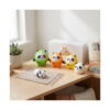 Set 5 squishy panda Set 5 squishy panda, cele cinci figurine pe o masă lângă fereastră: patru în costume colorate și una albă cu negru, cu cutia SpOki în spate.