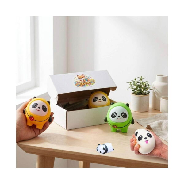 set-5-squishy-panda-utilizare Set 5 squishy panda, cutie albă Spoki pe o masă; mâini care țin un panda squishy galben și unul alb rotund