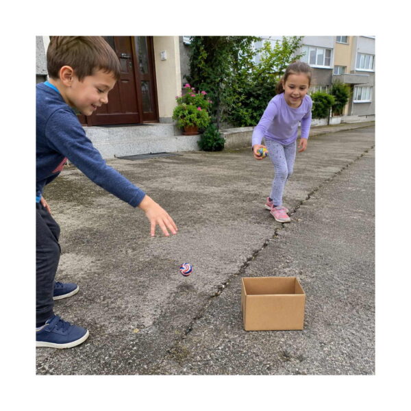 Set Aventuri Fly 11 în 1, afară, un băiat aruncă o minge spre o cutie de carton, iar o fetiță aleargă spre el