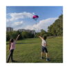 Set Aventuri Fly 11 în 1, doi copii într-un parc, cu mâinile ridicate spre o parașută cu figurină care coboară din cer