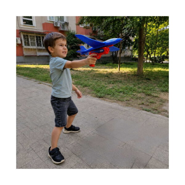 Set Aventuri Fly 11 în 1, băiat afară care ține lansatorul roșu cu avionul albastru montat